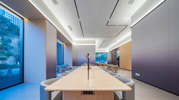 Un salón de conferencias moderno con una larga mesa, sillas y vistas al exterior.