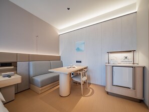 Een moderne hotelkamer met een bank, een tafeltje, een bureau en een minibars.
