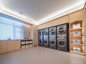 Ein Waschraum mit mehreren Waschmaschinen, Holzschränken und Aufbewahrungsboxen.
