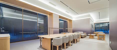 Une salle de conférence moderne, dotée d’une longue table, de chaises et d’une cloison en verre.