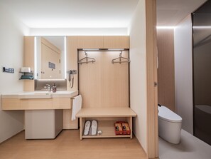 A modern bathroom with a sink, mirror, towel rack, and toilet.