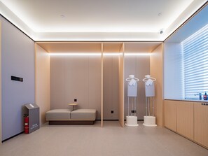 A modern, well-lit room with a sofa, a small table, and a fire extinguisher. - JI Hotel Xian Datang Everbright City Metro Stat (Xi'an)