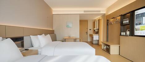 Habitación de hotel con dos camas, una mesita, un espejo y un televisor montado en la pared.