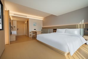 Una habitación de hotel con una cama grande, un escritorio y una silla.