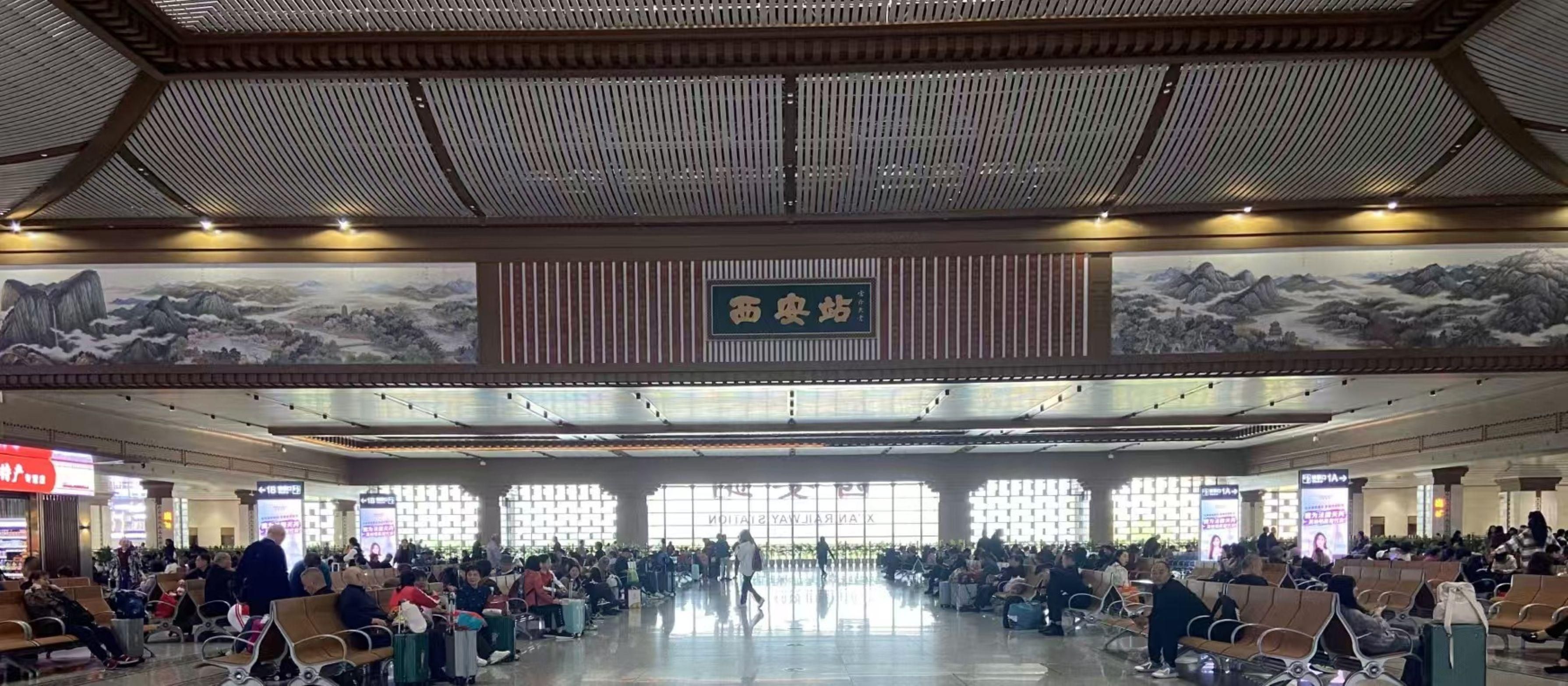 A spacious airport terminal with rows of seating and a large mural on the wall.
