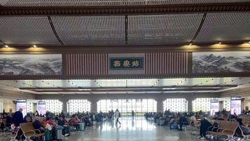 A spacious airport terminal with rows of seating and a large mural on the wall.