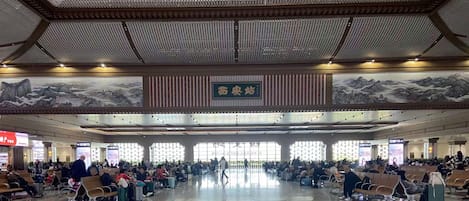 A spacious airport terminal with rows of seating and a large mural on the wall.
