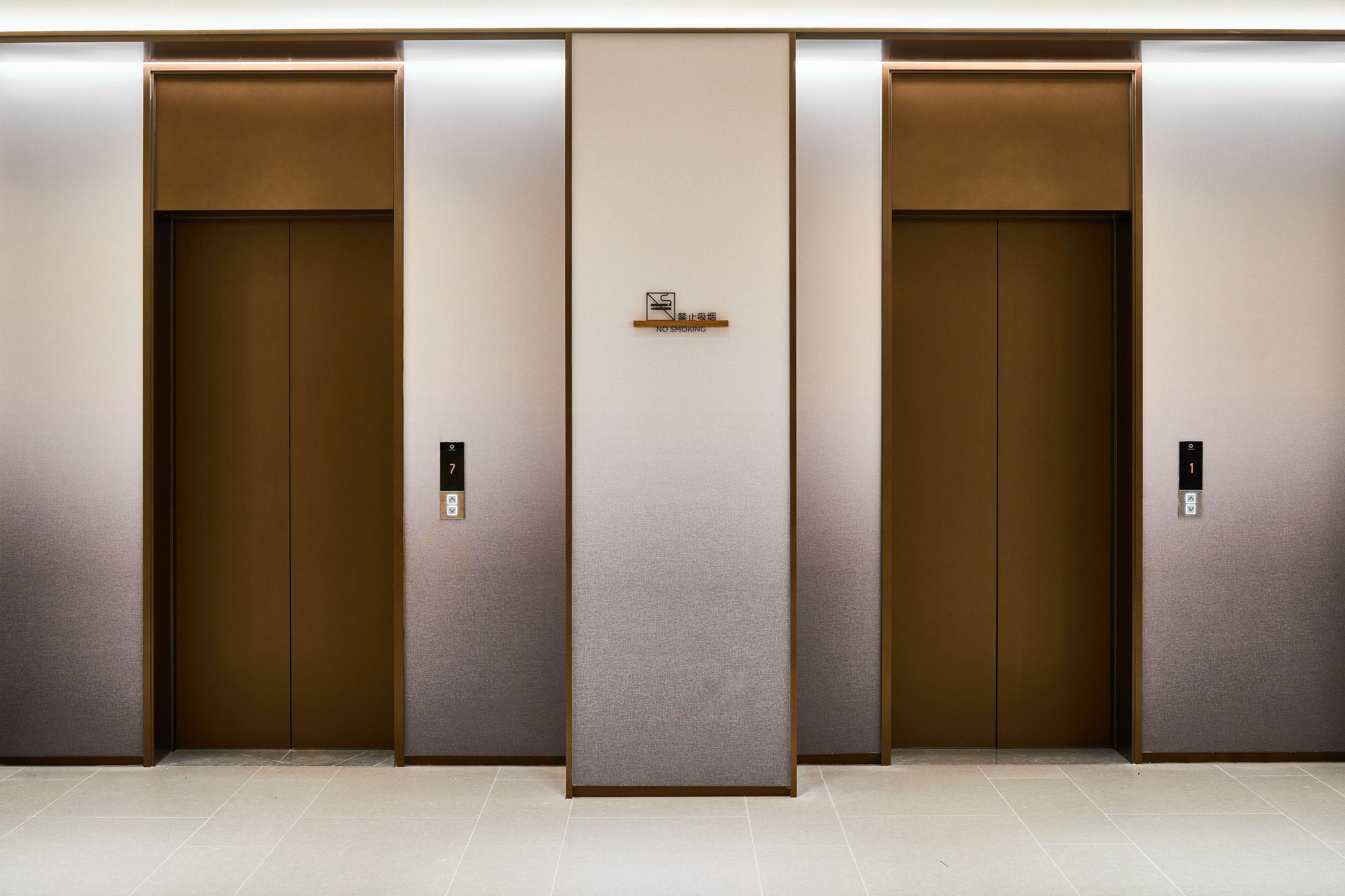 Three elevator doors with a 'NO SMOKING' sign above them.