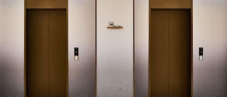 Three elevator doors with a 'NO SMOKING' sign above them.
