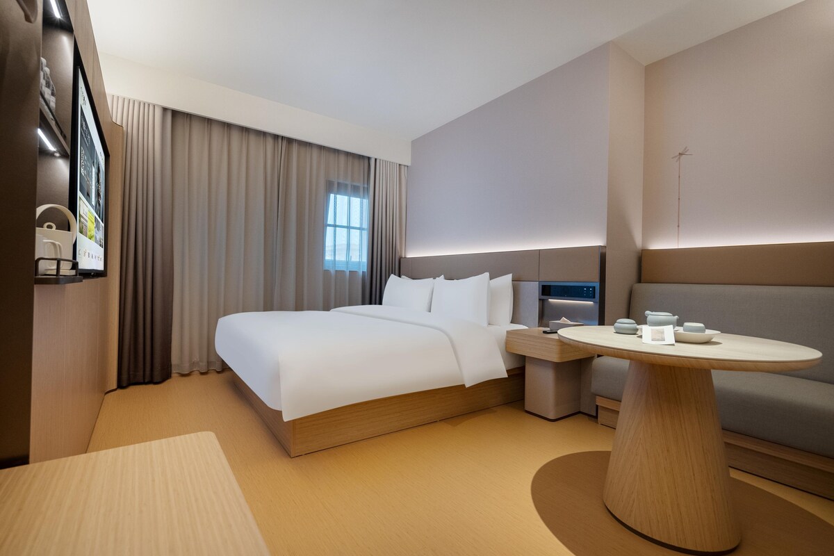 Una habitación de hotel moderna con cama, mesita de noche y una mesa redonda.
