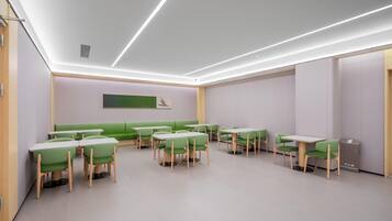 A modern interior with green seating and tables, a visible fire extinguisher, and a clean, minimalist design.