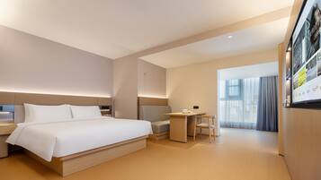 A modern hotel room with a large bed, a desk, and a chair.