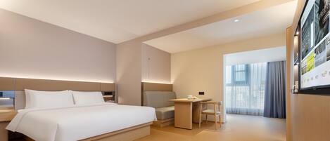 A modern hotel room with a large bed, a desk, and a chair.
