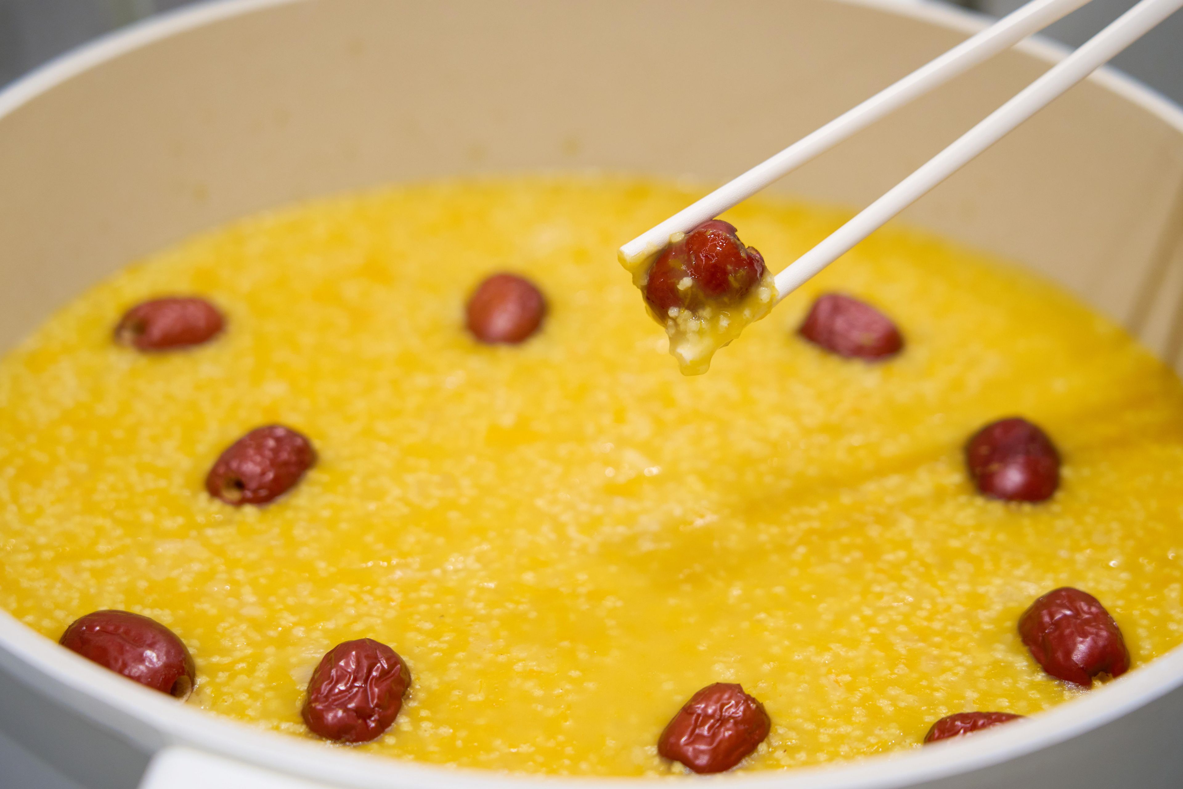 A pot of yellow porridge with raisins.