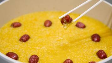 A pot of yellow porridge with raisins.