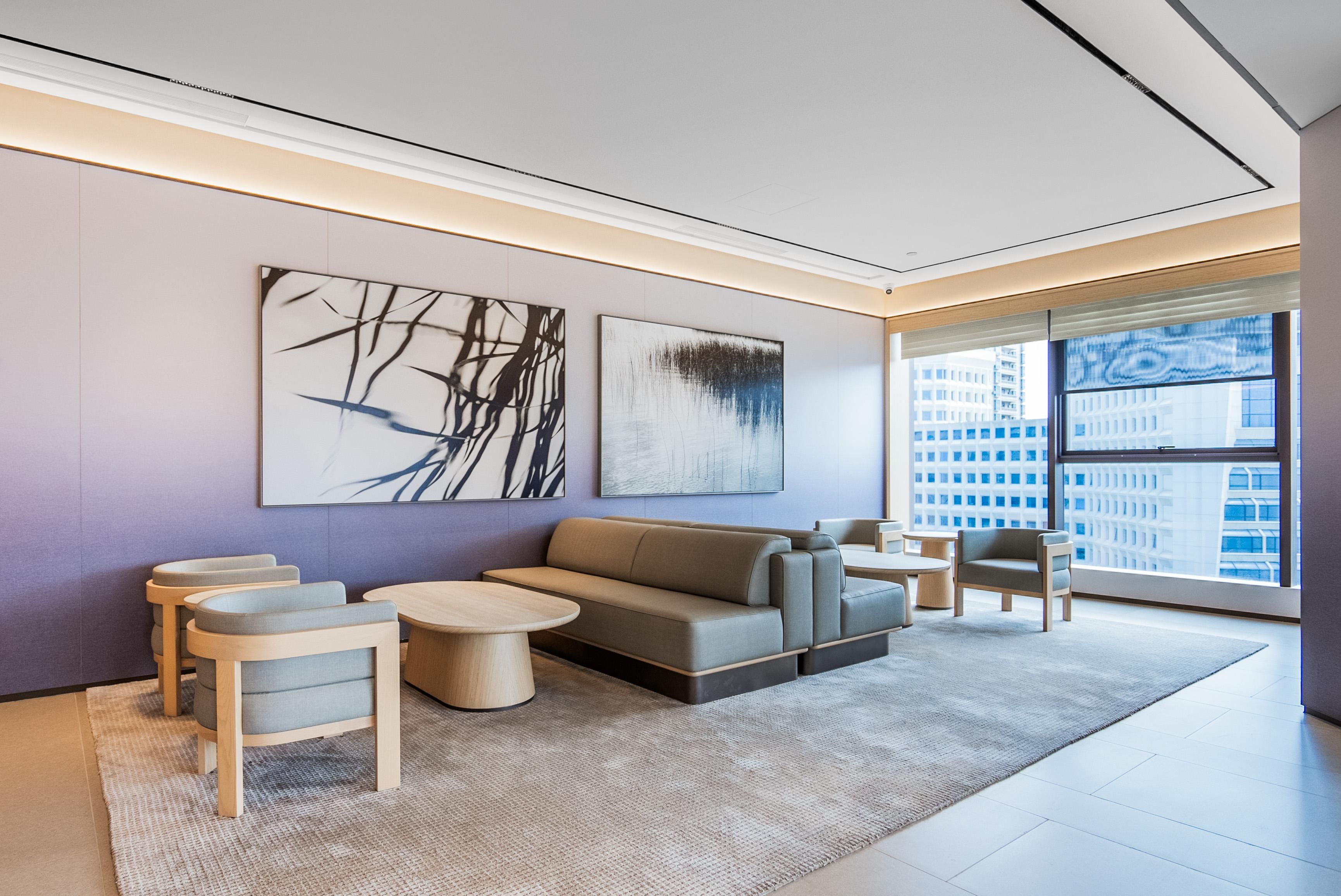A modern living room with a sofa, two armchairs, a coffee table, and abstract wall art.