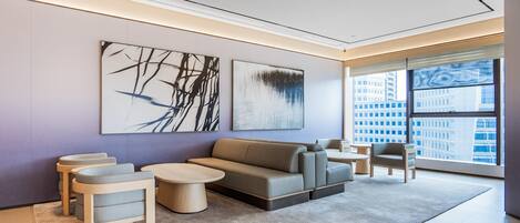 A modern living room with a sofa, two armchairs, a coffee table, and abstract wall art.