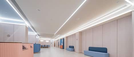 Un moderno vestíbulo de hotel con un mostrador de recepción alargado, zonas de estar y un diseño limpio y minimalista.