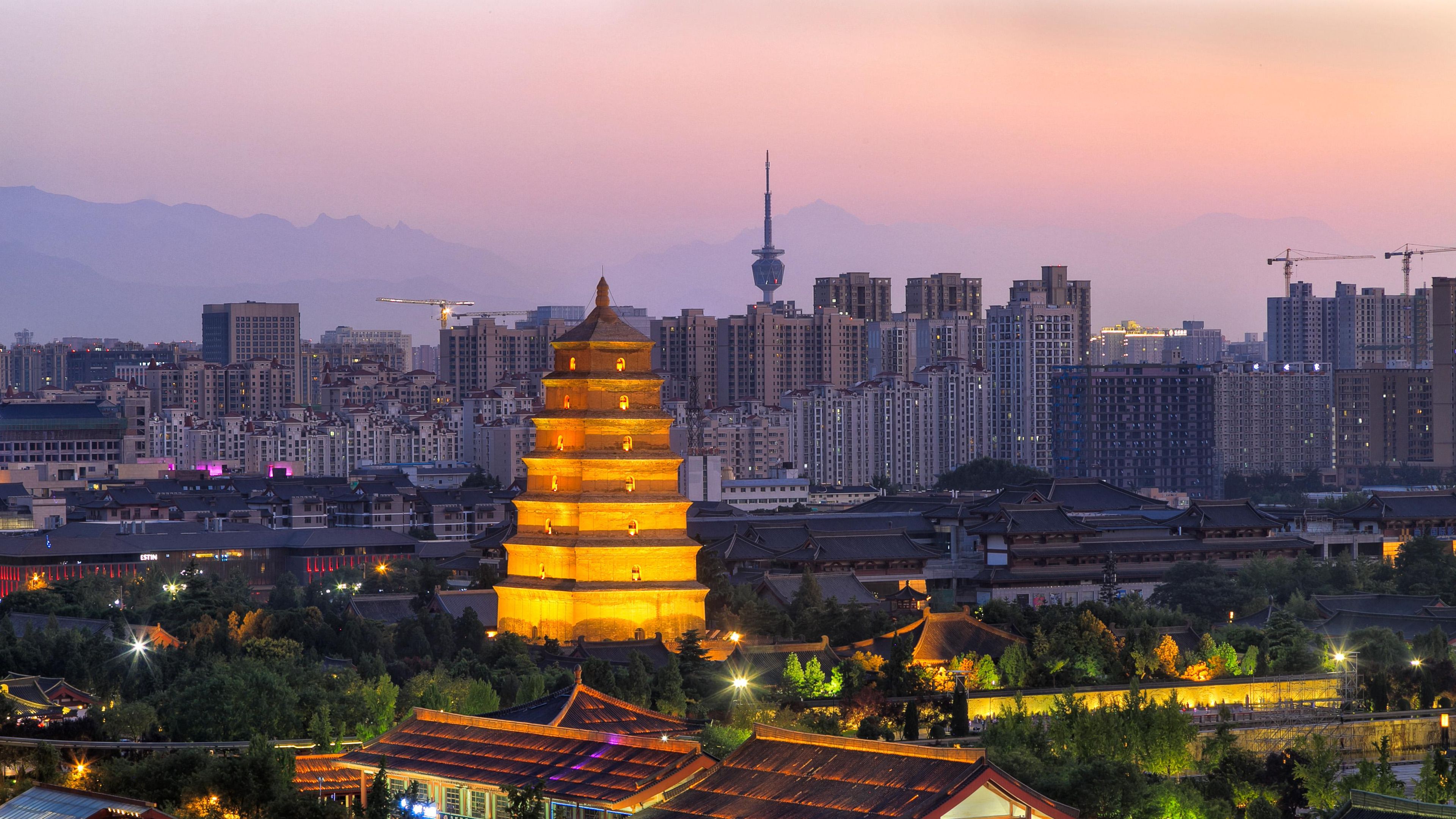 A traditional pagoda with multiple tiers, surrounded by modern high-rise buildings and a city skyline.