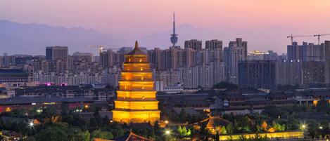 A traditional pagoda with multiple tiers, surrounded by modern high-rise buildings and a city skyline.