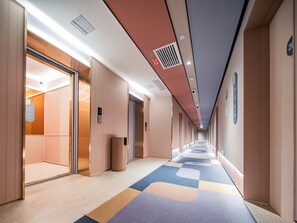 A hotel corridor with a check-in counter, elevator, and a patterned carpet. - Hanting Hotel Xian Bell Tower Dachaishi Metro St (Xi'an)
