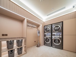 A modern laundry room with two wall-mounted washing machines, a drying rack, and storage bins. - Hanting Hotel Xian Bell Tower Dachaishi Metro St (Xi'an)