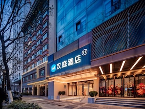 A hotel entrance with a modern facade, a prominent sign, and a staircase leading to the entrance. - Hanting Hotel Xian Bell Tower Dachaishi Metro St (Xi'an)