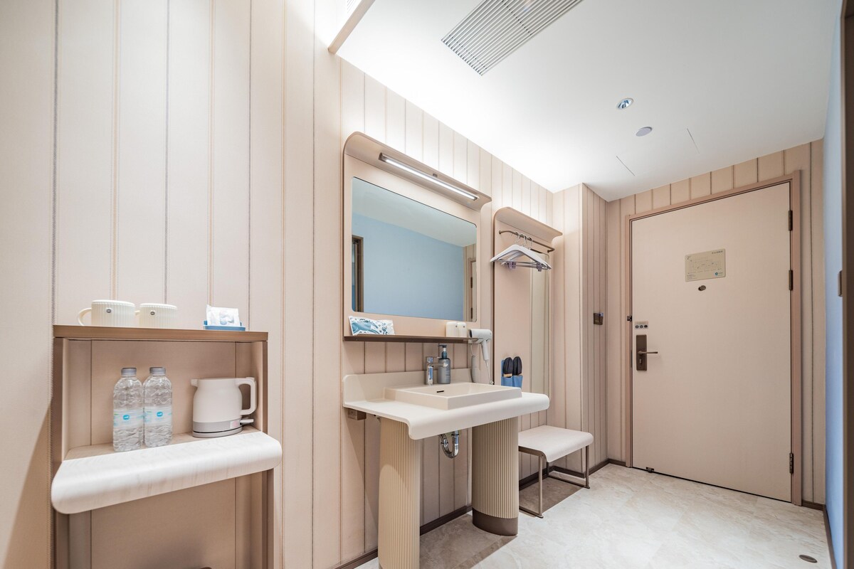 A modern bathroom with a large mirror, two sinks, a towel rack, and a toilet.