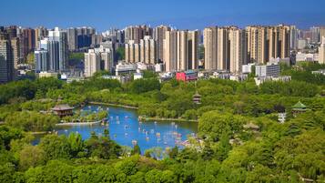 A cityscape with high-rise buildings and a park with a lake and boats.