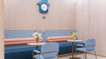 A room with a blue sofa, two chairs, a small table, and a wall clock.