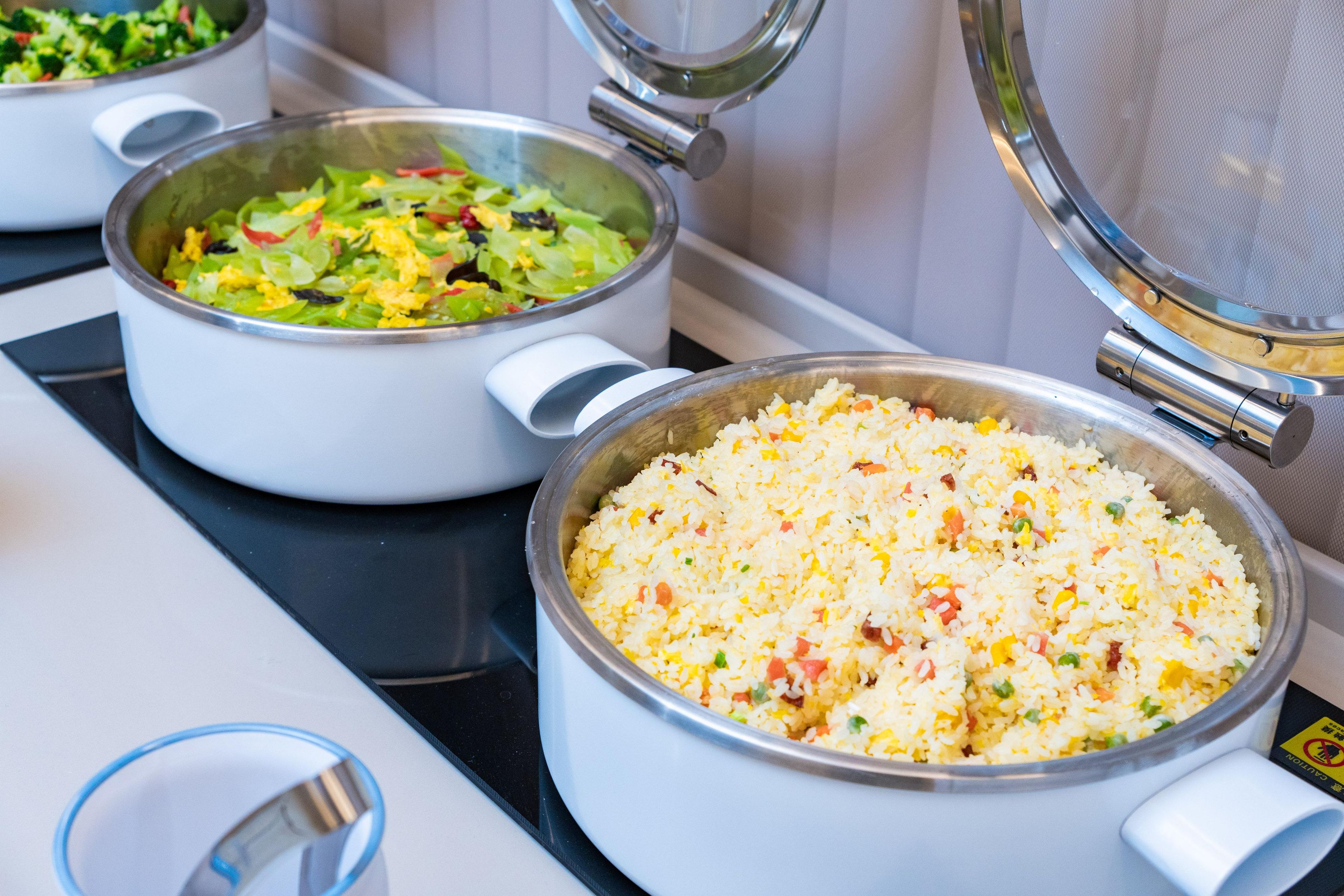 A kitchen with two pots on the stove, one containing a salad and the other containing fried rice.
