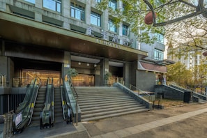 A hotel entrance with a modern design, featuring a staircase leading to the entrance, a covered area with escalators, and a sign indicating the hotel's name. - JI Hotel (Xi'an)