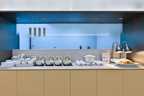 Une cuisine moderne avec des appareils électroménagers blancs, une cuisinière encastrée et un plan de travail agrémenté de divers ustensiles de cuisine.