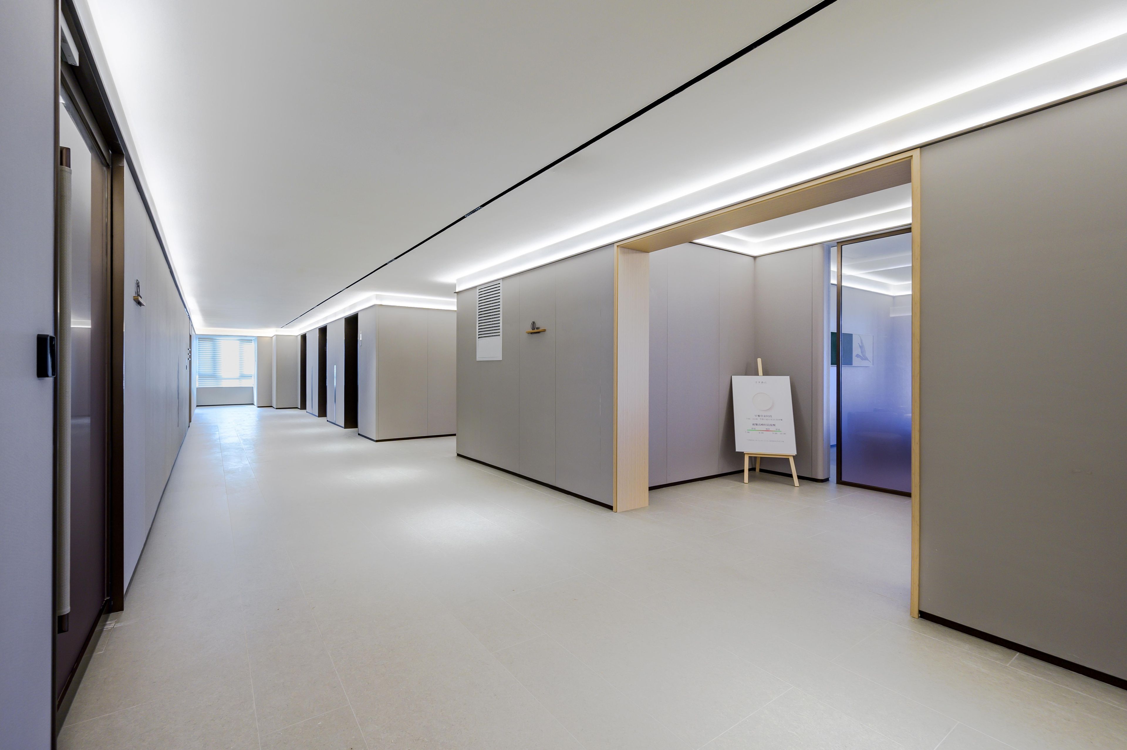 A modern hallway with a series of rooms, each with a door and a small sign on the wall.
