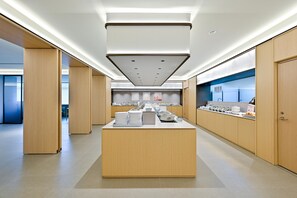 A modern kitchen with a central island, wooden cabinets, and a variety of kitchenware. - JI Hotel (Xi'an)