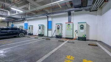 A parking garage with multiple electric vehicle charging stations, a car parked in one of the bays, and clear lane markings on the floor.