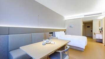 Una habitación de hotel con cama, zona de estar con mesa y baño.