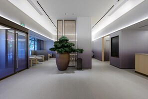 A modern lobby with a large potted plant, seating area, and a reception desk. - JI Hotel (Xi'an)