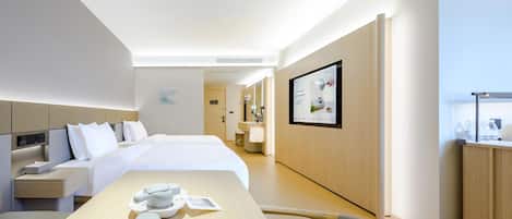 Ein modernes Hotelzimmer mit einem großen Bett, Nachttischen, einem Schreibtisch mit Stuhl, einem Badezimmer mit Spiegel und einem am Wand montierten Fernseher.