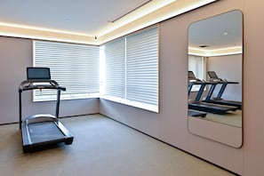 Un gimnasio moderno con cinta de correr, bicicleta estática y un espejo grande.