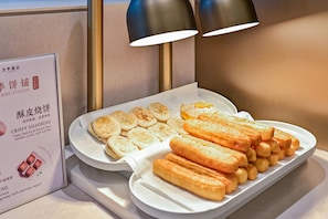 A tray of food items including crispy buns and bread rolls, with a sign indicating the location as 'Bing Station'. - JI Hotel (Xi'an)