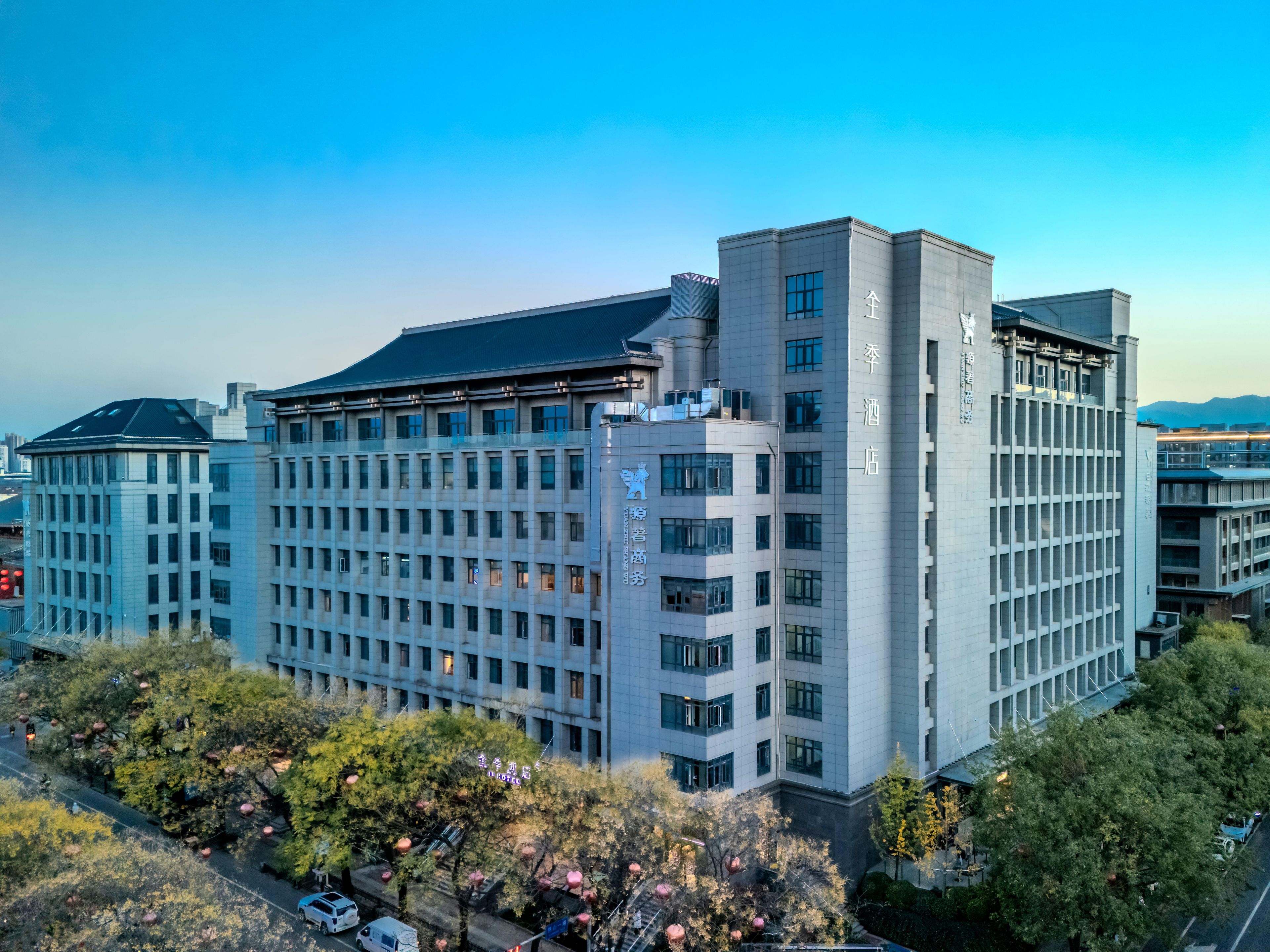 A multi-story hotel with a modern architectural design, featuring a prominent entrance and a large parking area.