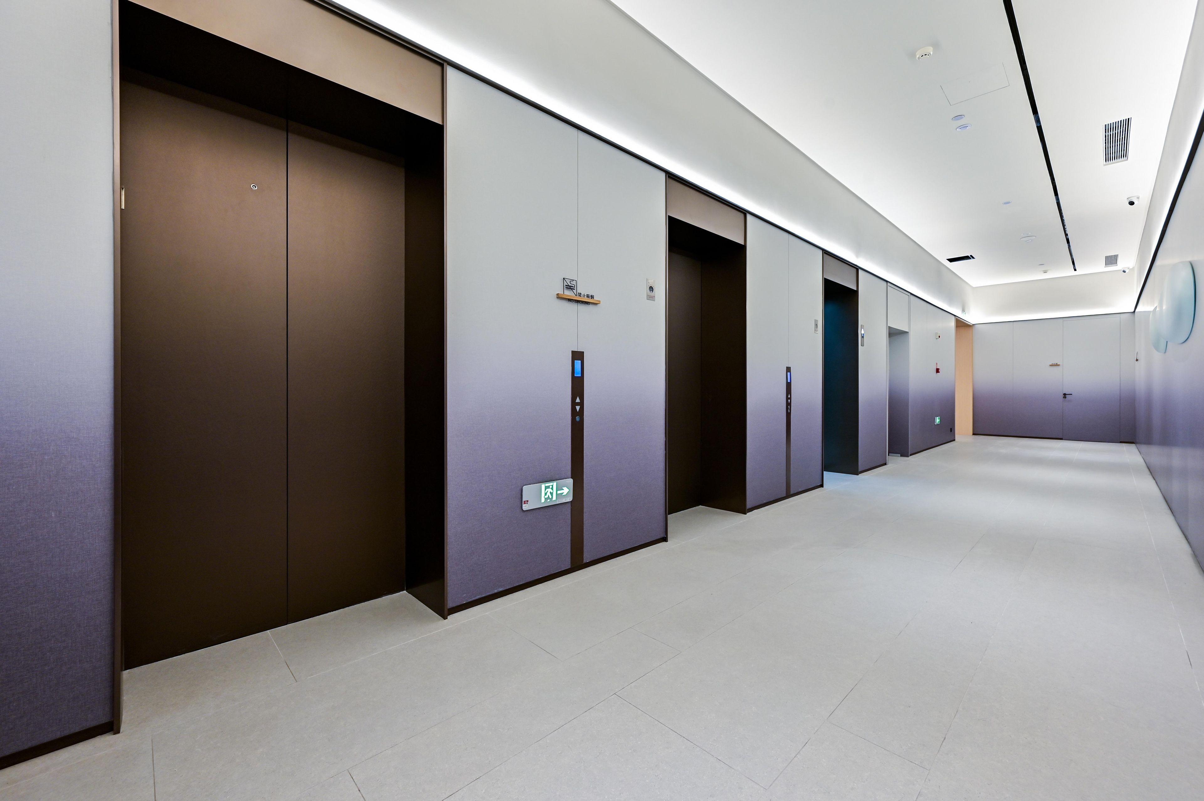Un pasillo moderno de hotel con varios ascensores y puertas.