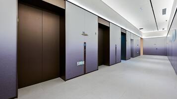 Un pasillo moderno de hotel con varios ascensores y puertas.