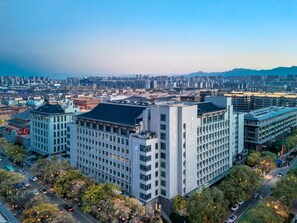 Un hotel de gran altura con varios pisos, rodeado de edificios urbanos y un paisaje urbano al fondo.