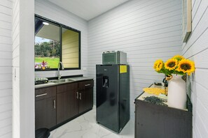 A compact kitchen with dark cabinets, a black refrigerator, a sink, and a window with a view of greenery.