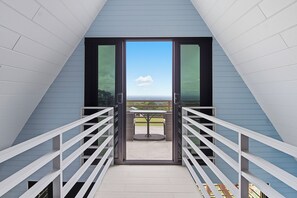 Un balcon avec une table et des chaises, une vue dégagée sur le ciel et une balustrade.