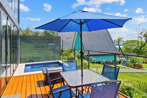 A poolside area with a hot tub, a table with chairs, and a blue umbrella. - Junglo Resort And Spa (Peñas Blancas)