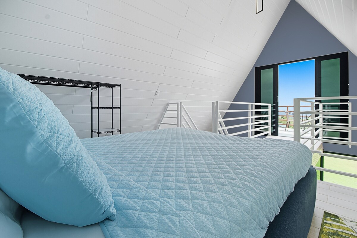 Un dormitorio con cama, una escalera y un balcón con barandilla.
