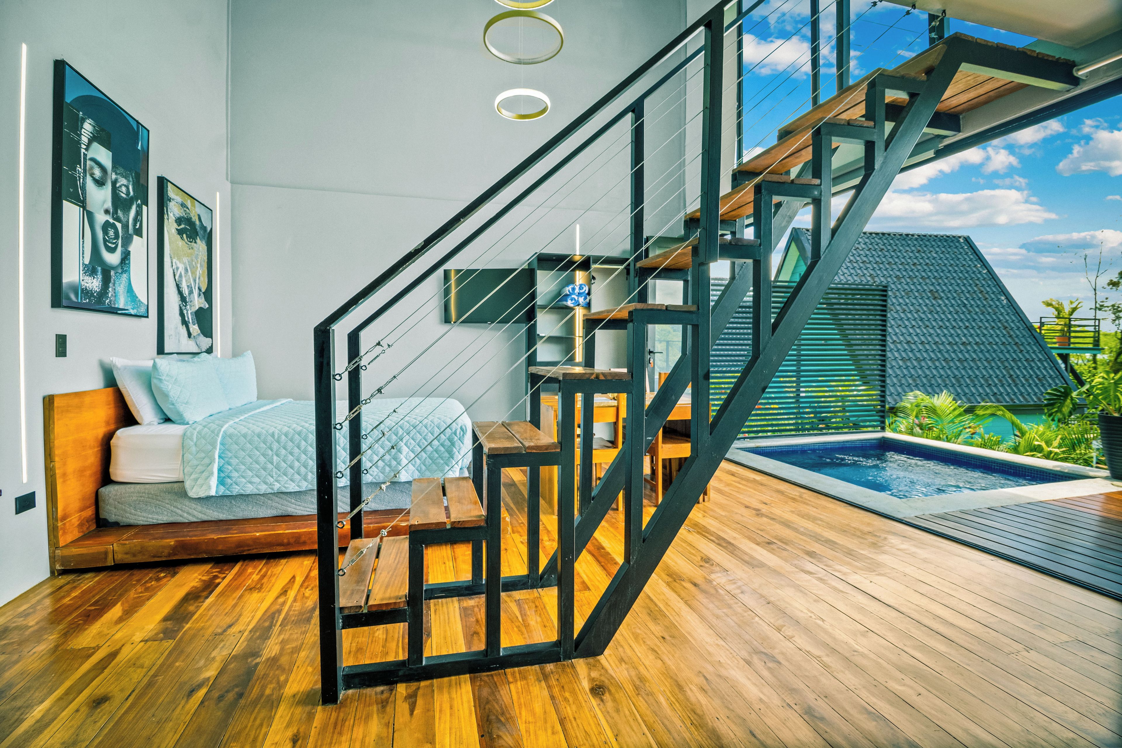 A modern interior with a staircase, a bed, a small pool, and artwork on the walls.